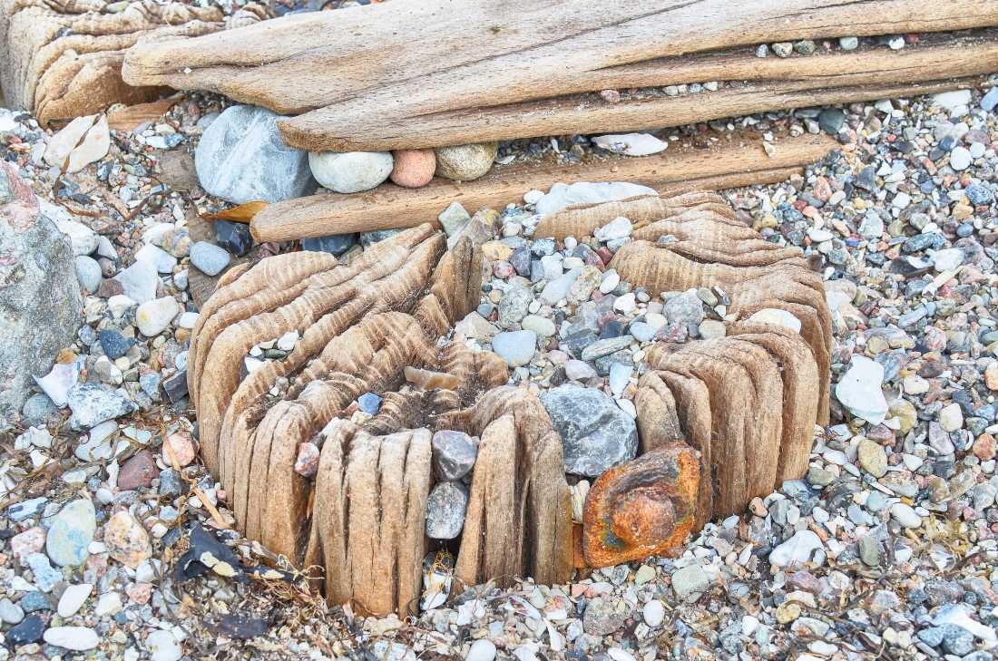 Irk Boockhoff, Verwittertes Holz am Strand 3 (Strand,  Holz, verwittert, morbid, Kiesel, Steinchen, maritim, Fotokunst, Treppenhaus, Wohnzimmer, Badezimmer, Wunschgröße, bunt)