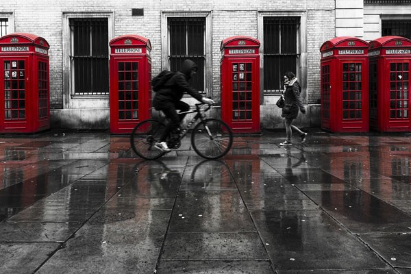 Vladimir Kostka, PHONE BOOTHS II (rote Telefonzellen, England, Regen, Pfützen, Radfahrer, Häuser, Reflexionen, Colorspot, Fotokunst, Wunschgröße, Wohnzimmer, Treppenhaus, rot/schwarz/weiß)