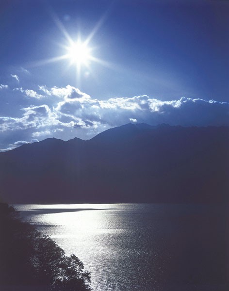 Gerd Weissing, IDYLLIC LAKE II (Landschaft, Sonne, Sonnenstrahlen, Himmel, See, Berge, Idylle, Wohnzimmer, Treppenhaus, Fotokunst, Wunschgröße, blau/grau)