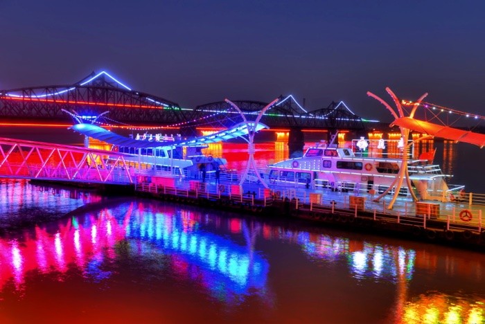 Hady Khandani, HDR - ILLUMINATED BOATS ON YALU RIVER - DANDONG - CHINA 02 (Yalu, Fluss, Boote, Beleuchtung, Spiegelungen, neonfarben, Nachtszene, Partytime, Dandong, China, Fotokunst, Wohnzimmer, Treppenhaus, Jugendzimmer, Wunschgröße, bunt)