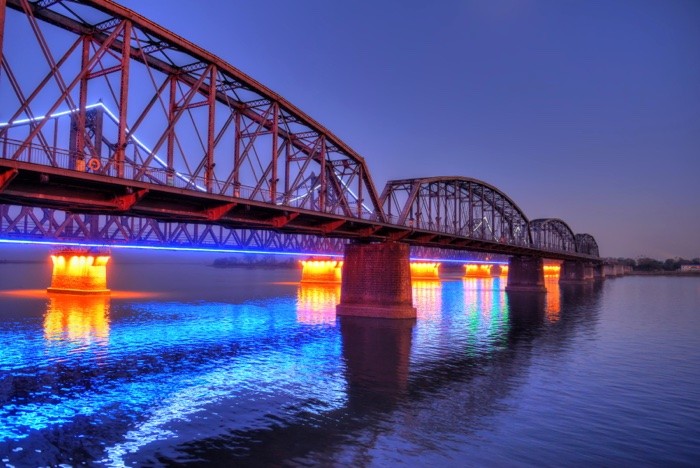 Hady Khandani, HDR - ILLUMINATED SINO-KOREAN FRIENDSHIP BRIDGE OVER YALU RIVER BETWEEN CHINA AND NORTH KOREA - DANDONG 04 (Yalu, Fluss, Brücke, Freundschaftsbrücke, Bauwerk, Konstruktion, Beleuchtung, Spiegelungen, neonfarben, Dämmerung, Dandong, China, Nordkorea, Fotokunst, Wohnzimmer, Treppenhaus,  Wunschgröße, bunt)