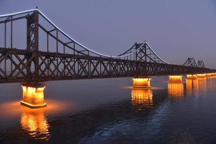 Hady Khandani, ILLUMINATED SINO-KOREAN FRIENDSHIP BRIDGE OVER YALU RIVER BETWEEN CHINA AND NORTH KOREA - DANDONG 1 (Yalu, Fluss, Brücke, Freundschaftsbrücke, Bauwerk, Konstruktion, Beleuchtung, Spiegelungen, Dämmerung, Dandong, China, Nordkorea, Fotokunst, Wohnzimmer, Treppenhaus,  Wunschgröße, bunt)