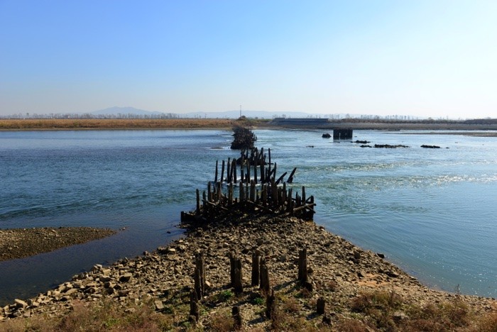 Hady Khandani, ROTTEN BRIDGE ACROSS YALU RIVER FORM CHINA TO NIRTH KOREA - NEAR DANDONG (Brücke, zerstörte Brücke, Bauwerk, Konstruktion, Zerstörung, Dandong, China, Nordkorea, Fotografie, Wohnzimmer, Treppenhaus, Wunschgröße, bunt)