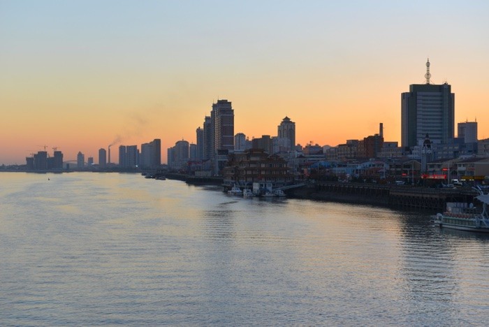 Hady Khandani, SUNSET OVER DANDONG - RIVERSIDE VIEW - CHINA 1 (Yalu, Fluss, Sonnenuntergang, Skyline, Hochhäuser, Dämmerung, Dandong, China, Fotokunst, Wohnzimmer, Treppenhaus, Jugendzimmer, Wunschgröße, bunt)