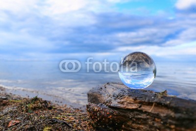 Alaskajade, Transparent glass ball on a log reflecting calm blue water of a lake (durchsichtig, spiegel, betrachtung, futuristisch, surreal, meer, klarer himmel, frieden, kristallkugel, kreis, fantasy, vorstellung, wahrsagerei, kreativität, sphäre, glamour, reflektor, ball, urlaub, strand, see, wasser, nass, küstenlinie, küst)
