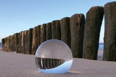 Gerhard Rossmeissl, Kugel im Sand (Landschaft,  Kugel, Glaskugel, Meer, Strand, Sand, Pfosten, Wellenbrecher, Reflexion, Spiegelung, Nordsee, Wellness, Entspannung, Badezimmer, Schlafzimmer, Wunschgröße, Fotokunst, Arztpraxis, zeitgenössisch, bunt)