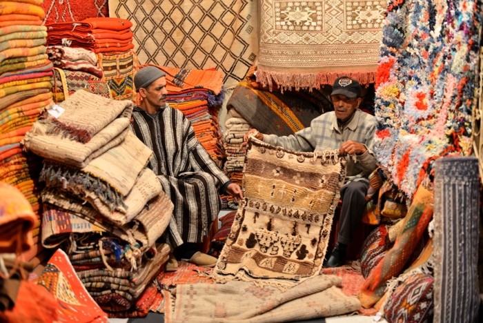 Hady Khandani, TWO MEN IN A CARPET STORE - MARRAKECH - MOROCCO (HADYPHOTO, Fotografie,  Geschäft, Basar, Teppiche, Teppichverkäufer, Marokko, Afrika, Wohnzimmer, Treppenhaus, Wunschgröße, bunt)