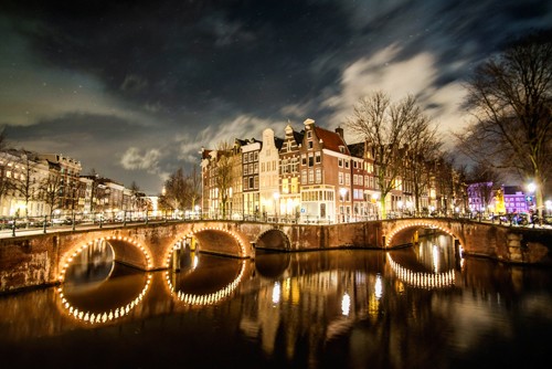 Sandrine Mulas, Amsterdam Illuminated Bridge (Metropole, Städte, Niederlande, Fotokunst, Architektur, Häuser, historisch, Brücke, Nachtszene, Beleuchtung, Gracht, Spiegelungen,  Treppenhaus, Wohnzimmer, Wunschgröße, bunt)