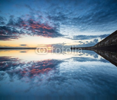 veneratio, Beautiful vibrant sunrise sky over calm water ocean with lightho (landschaft, seelandschaft, meer, ozean, wasser, leuchtturm, gebäude, wand, schranke, bewegungsunschärfe, verfärbt, bunt, lebendig, hafen, himmel, wolken, moody, dramatisch, blau, orange, rosa, grau, morgens, morgengrauen, sunrise, formation, sonn)