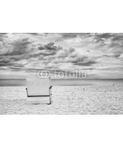 MaciejBledowski, Hooded wicker basket chair on an empty beach, black and white filter applied.