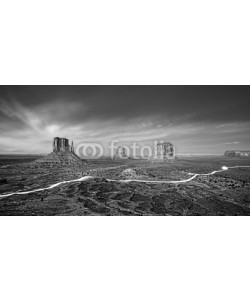 MaciejBledowski, Black and white photo of Monument Valley with car lights trails at night, USA.