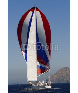 biker3, Rear shot of a yacht at full sail in the ocean against the hill and clear sky