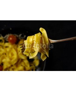 fotoatelie, Fettuccini pasta with cherry tomatoes and bacon on a fork.
