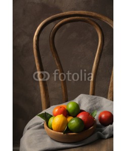 Africa Studio, Composition of different citrus fruits in bowl on wooden chair
