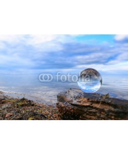 Alaskajade, Transparent glass ball on a log reflecting calm blue water of a lake
