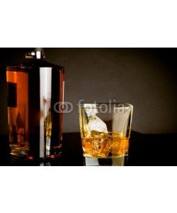 donfiore, whiskey with ice in glass near bottle on dark background