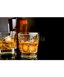 donfiore, whiskey in glasses in front of bottle on black background